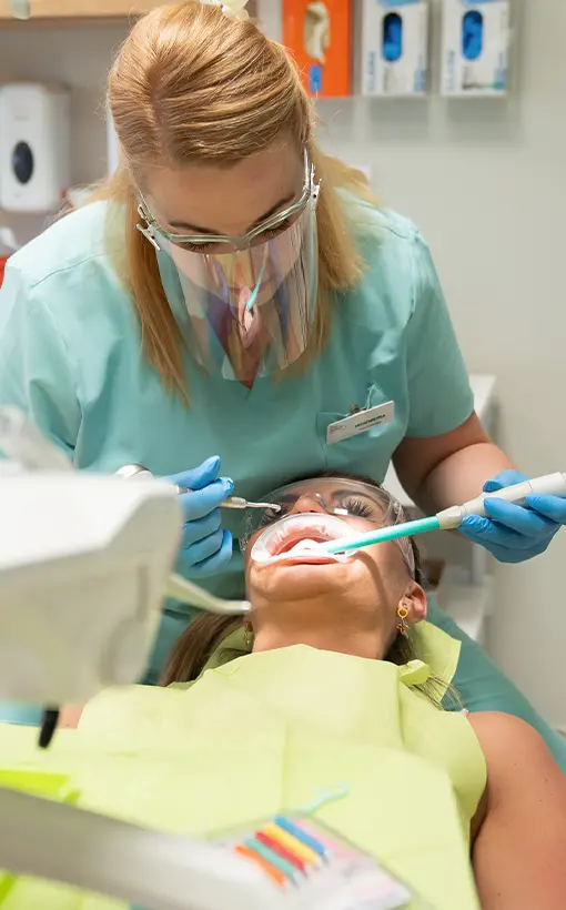 Kobieta na fotelu dentystycznym podczas zabiegu higienizacji jamy ustnej.
