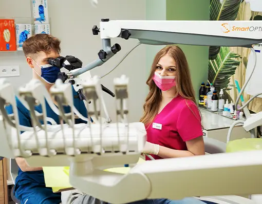 Stomatolodzy pracujący przy użyciu mikroskopu w gabinecie dentystycznym.