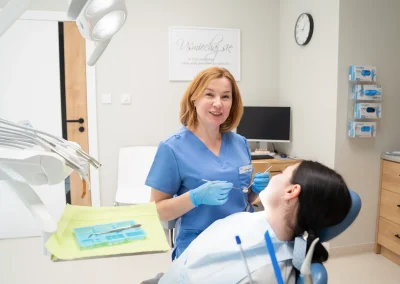 Dentystka badająca pacjentkę siedzącą na fotelu stomatologicznym.