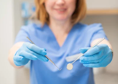 Dentystka trzymająca w dłoniach lusterko i zgłębnik stomatologiczny.